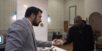 Kazi Mannan handing free meal to a man.