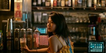 Woman at a bar holding a glass.