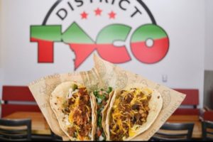 Two tacos in front of a logo