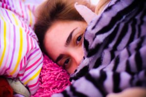 A woman lying under a blanket.