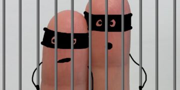 Two fingers behind bars representing criminals.