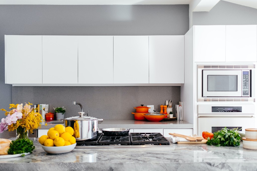 A kitchen with white cabinets and a gray countertop.