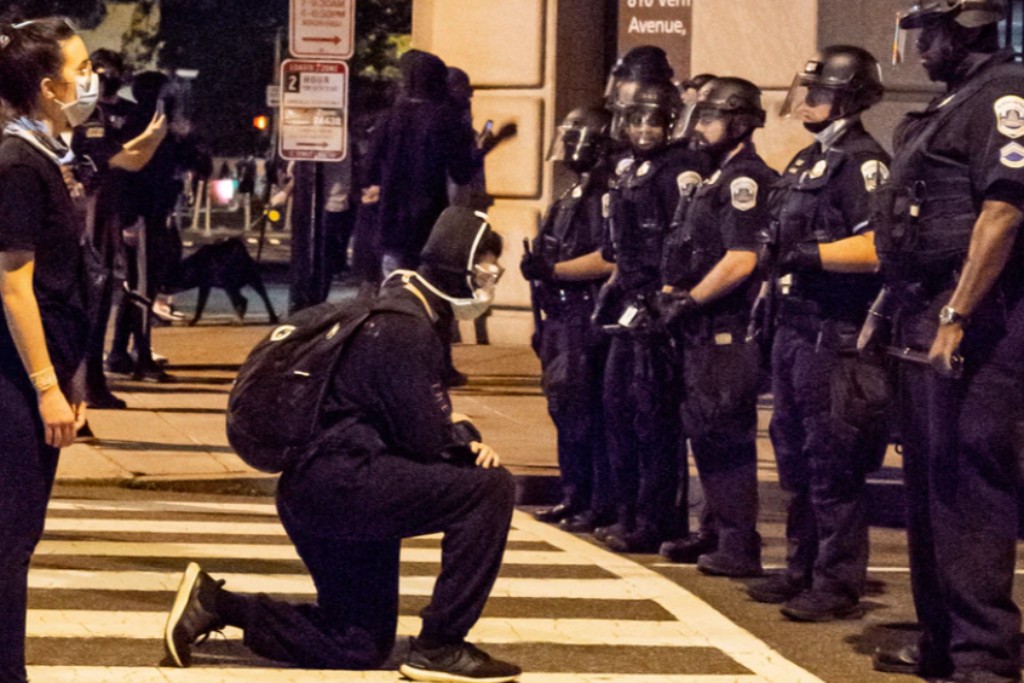 A demonstrator taking a knee in front of police officers in DC.