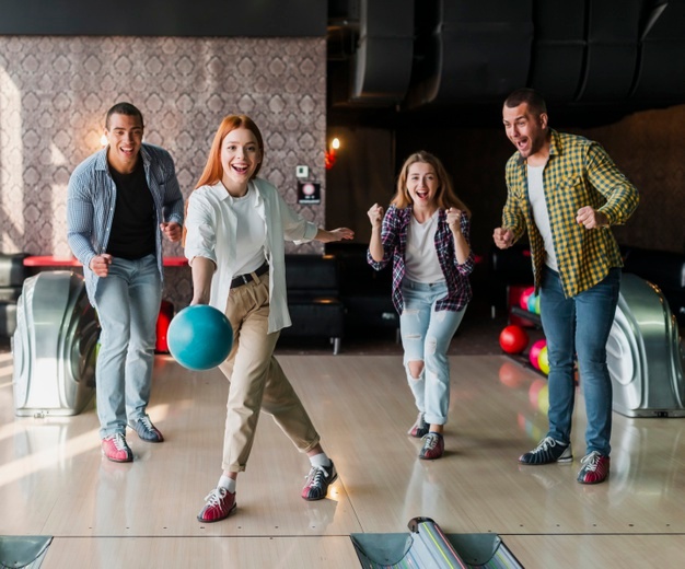 Young woman throwing bowling ball on the alley 