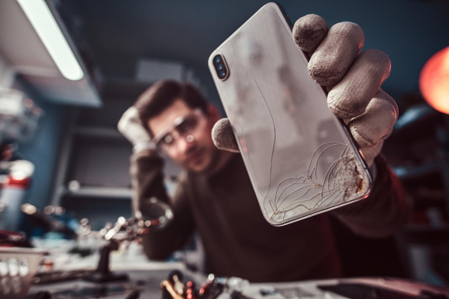 Technician showing a smartphone with a broken screen getting fixed in a repair shop in Washington DC